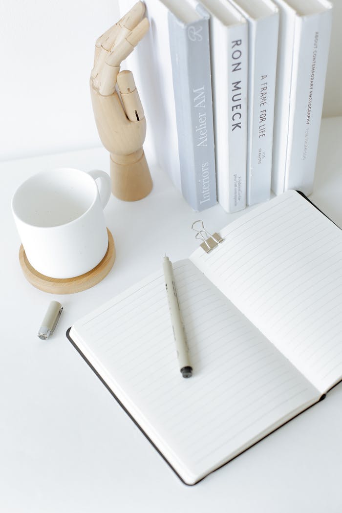 A clean and organized desk setup featuring an open notebook, books, and a mug, perfect for a modern workspace.